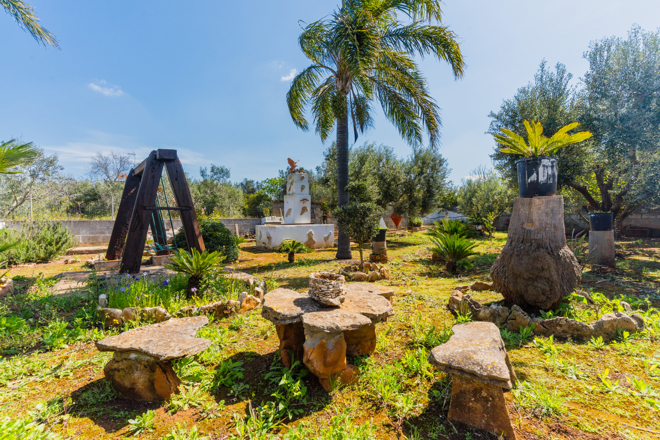 Area giochi con altalene nel giardino di Villa Li Giannelli tra alberi da frutto.