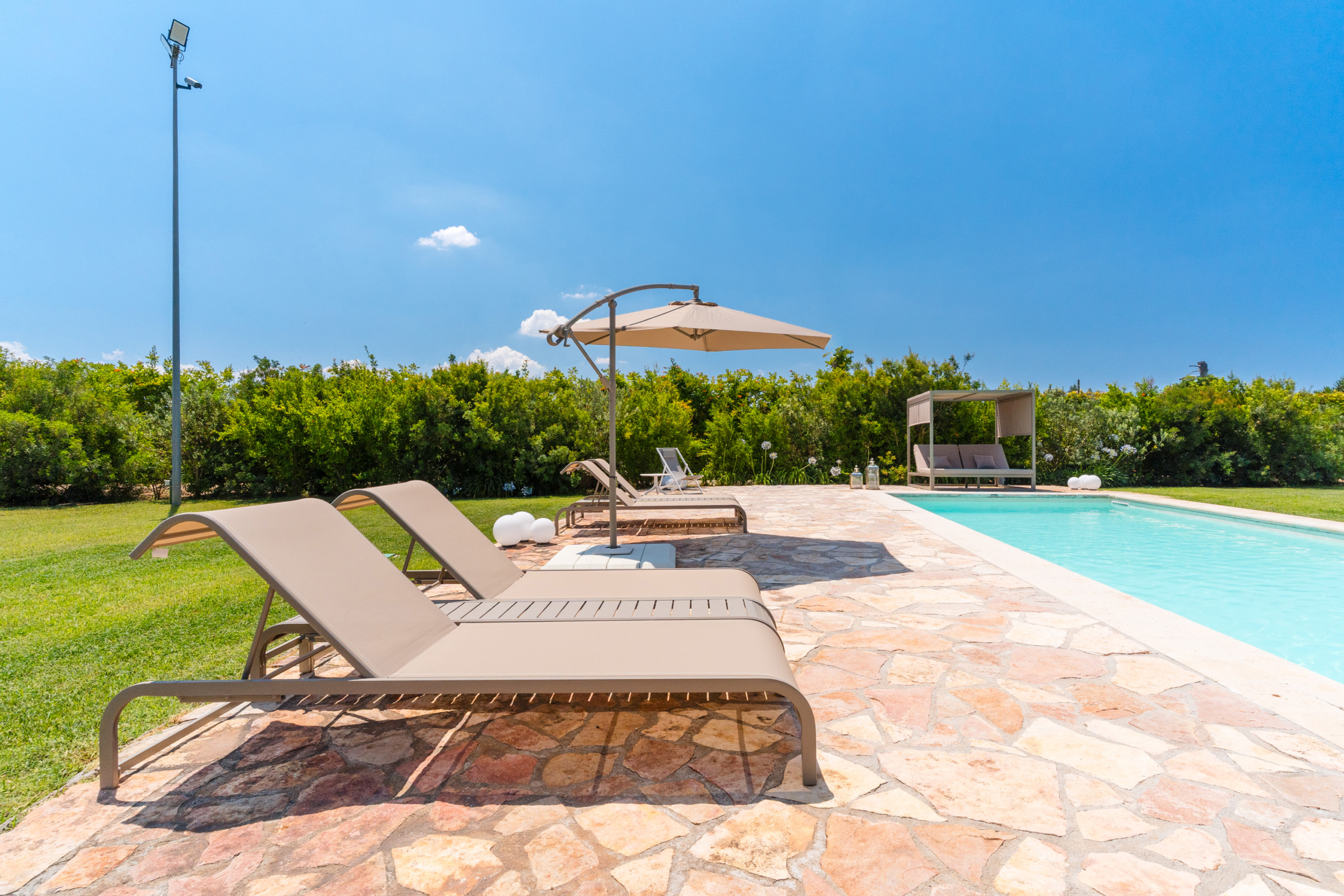lettini piscina con divanetto e ombrellone attico villa cucci