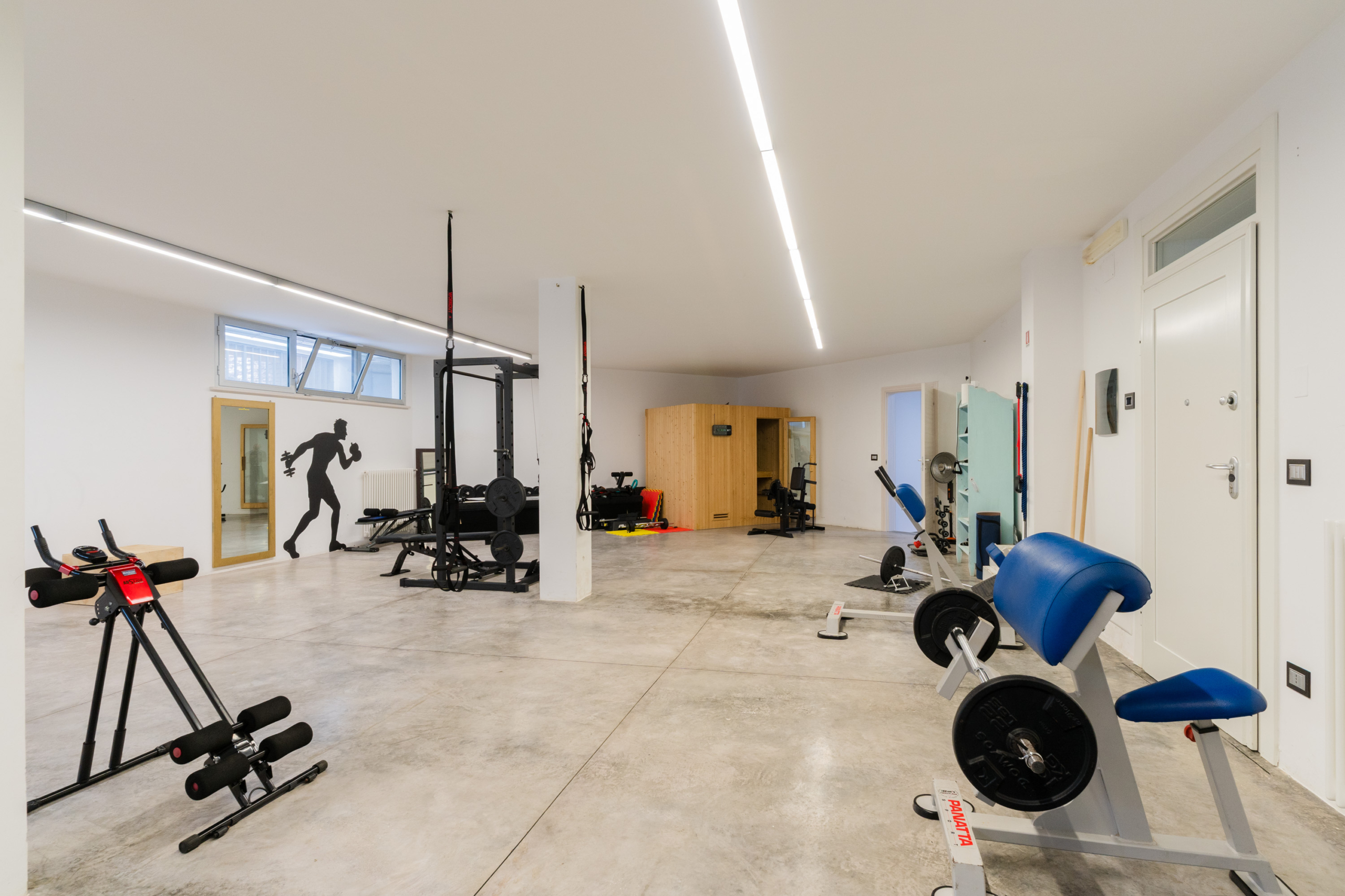 attrezzi e sauna con finestra e specchio della palestra di attico villa cucci